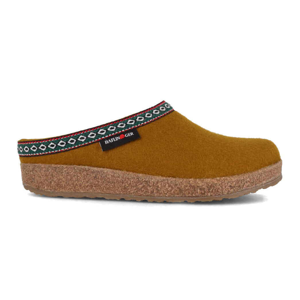 Side view of a Haflingers GZ Mustard - Womens clog with a decorative ethnic pattern on the strap and a cork footbed, isolated on a white background.