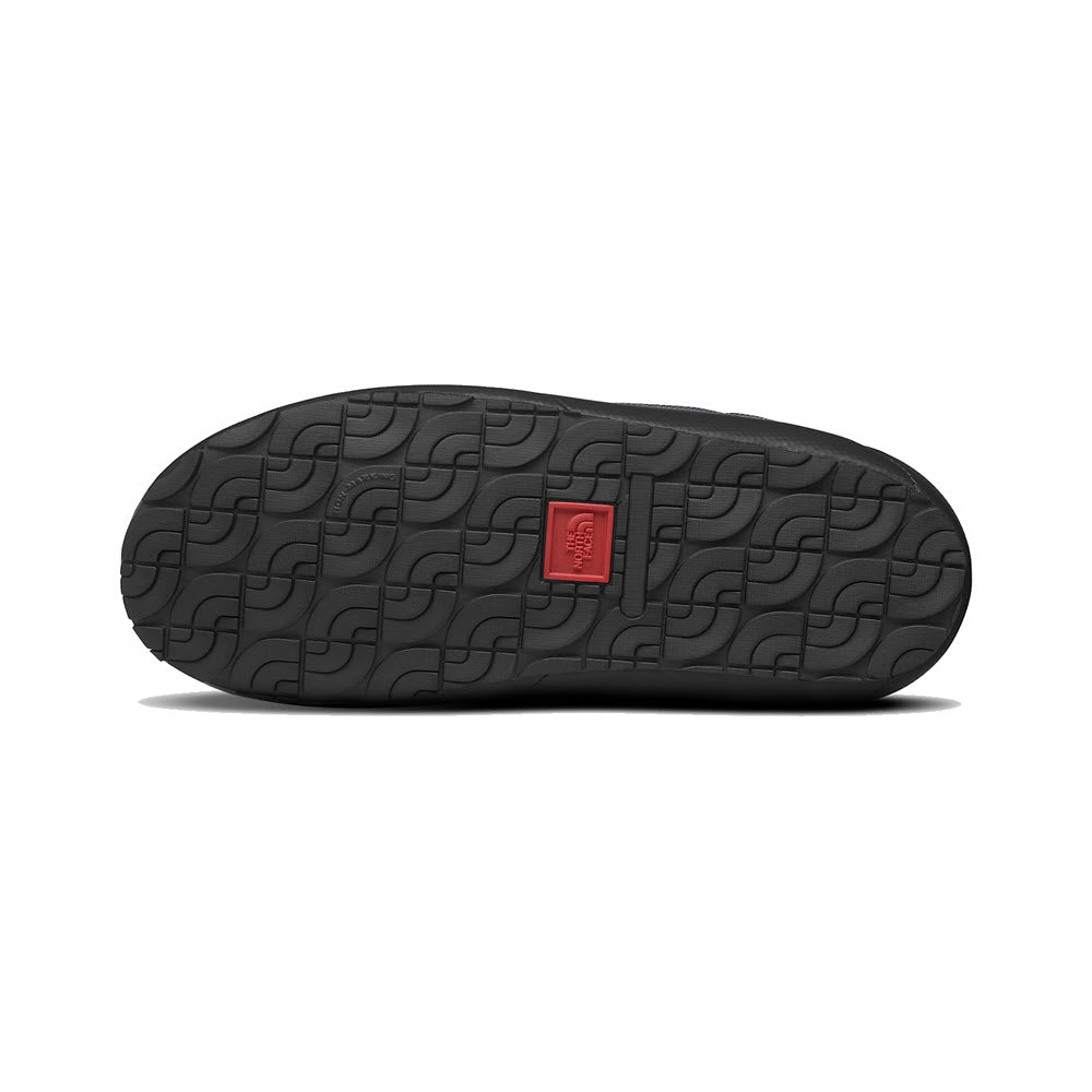 Sole of a North Face shoe with a black high-traction rubber outsole and a red logo square in the center.