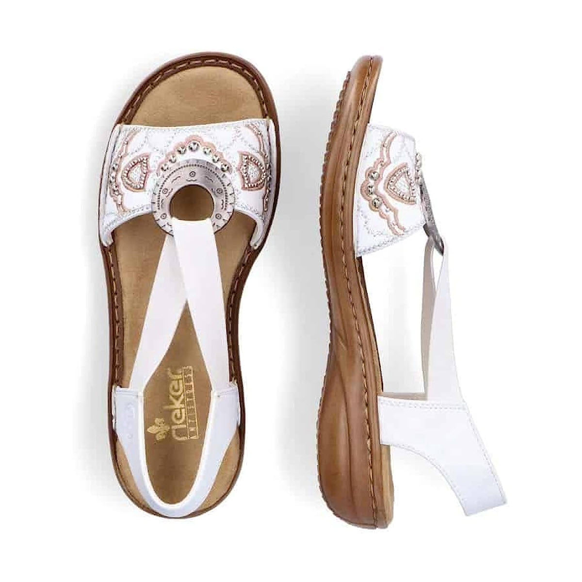 A pair of white and brown women&#39;s Rieker slingback flat sandals with decorative embroidery and a circular emblem on the top, viewed from above.