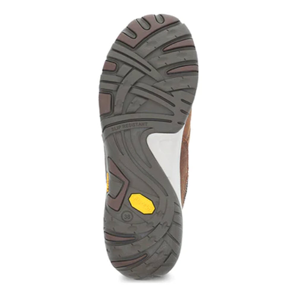 A close-up view of the sole of a Dansko shoe, featuring a multi-patterned tread design in gray and tan with a yellow rectangle. This is part of the slip-resistant Vibram rubber outsole.