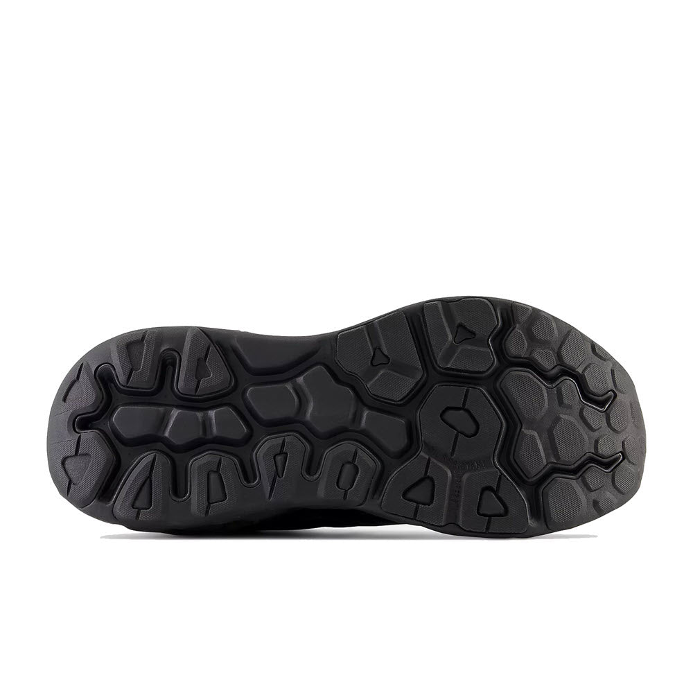 Black slip-resistant rubber sole of a New Balance shoe with a hexagonal and arrow-shaped tread pattern, isolated on a white background.