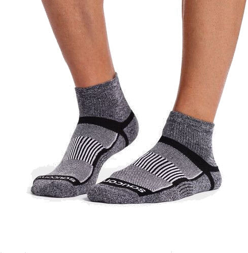 A pair of feet wearing Saucony Inferno Cushion Quarter Black/White socks with striped patterns on a white background.