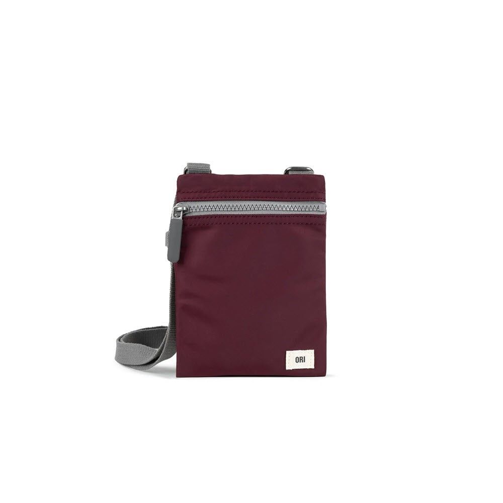 Small Ori London Chelsea crossbody bag in plum made of recycled material, featuring a zippered closure and an adjustable gray strap, displayed against a white background.