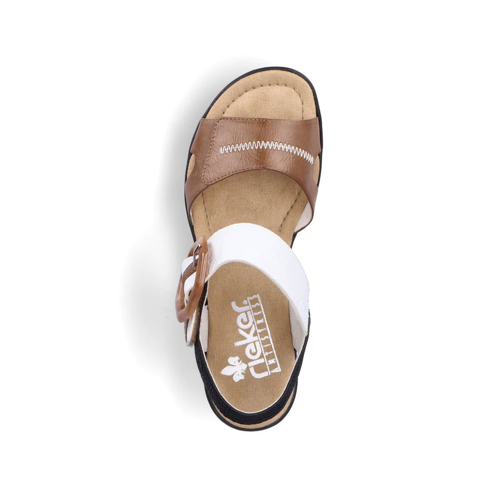 Top-down view of a single brown and white Rieker Big Buckle Wedge Tan Multi sandal with adjustable straps, featuring a logo on the insole, isolated on a white background.