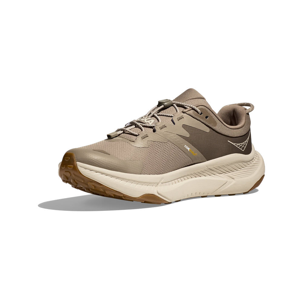 A single beige Hoka Transport Dune/Eggnog trail running shoe made from eco-friendly materials, with robust tread, featuring a low cut design and lace-up front, displayed against a white background.