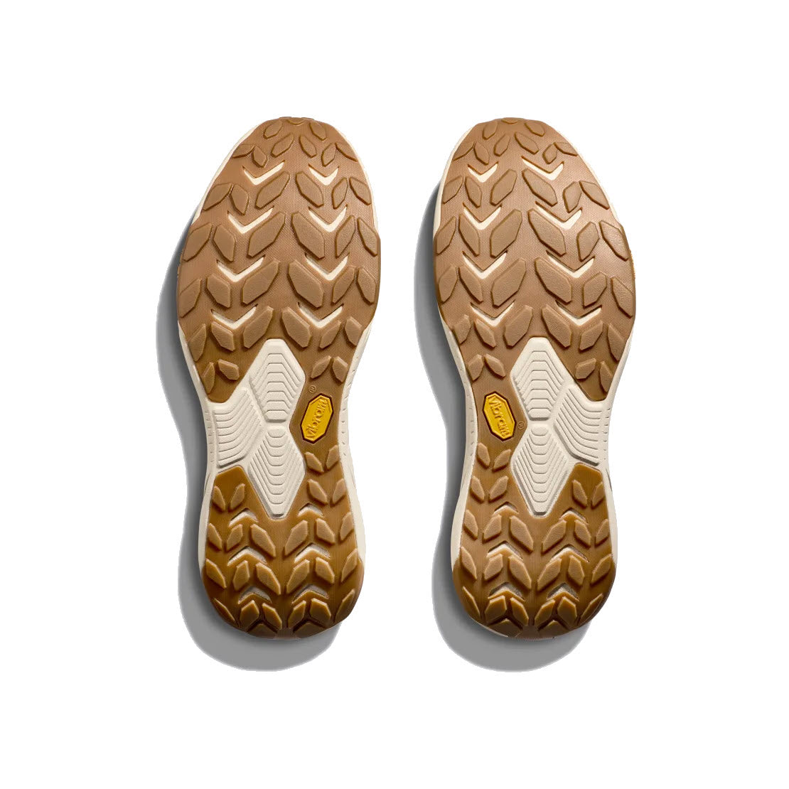 A pair of Hoka shoe soles made from eco-friendly materials, with a brown tread pattern and white and yellow accents, displayed on a white background.