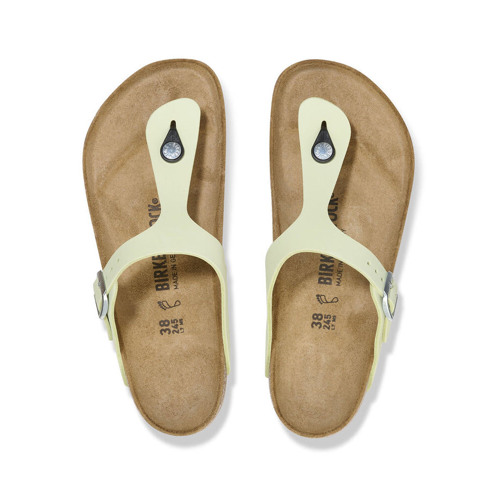 A pair of pale yellow nubuck leather Birkenstock Gizeh sandals with toe loops, viewed from above on a white background.