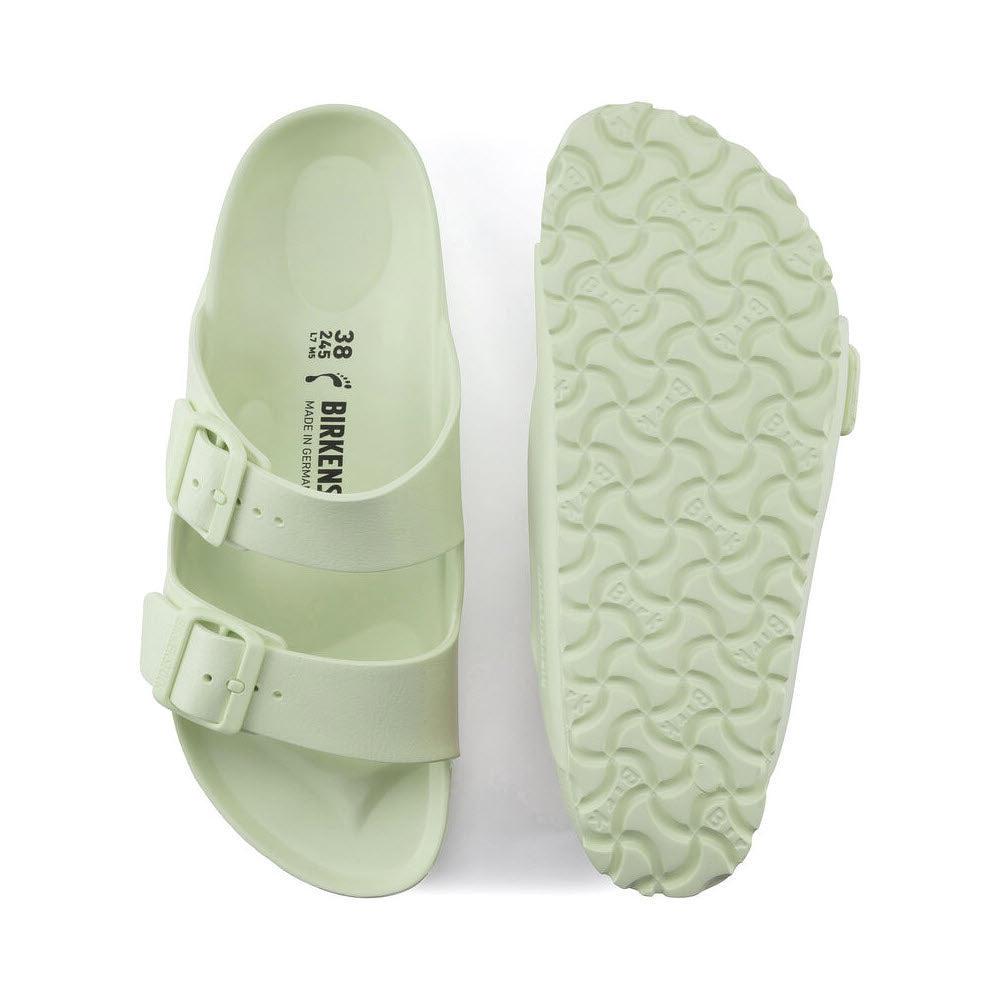 A pair of lightweight Birkenstock Arizona Eva Faded Lime sandals with two straps and buckles, displaying the top and textured sole of one sandal, on a white background.