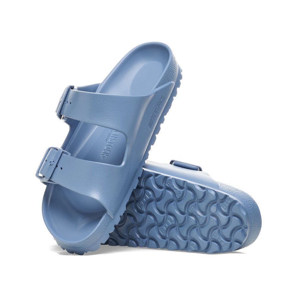 A pair of lightweight Birkenstock Arizona EVA Elemental Blue sandals with buckle detail and textured soles against a white background.
