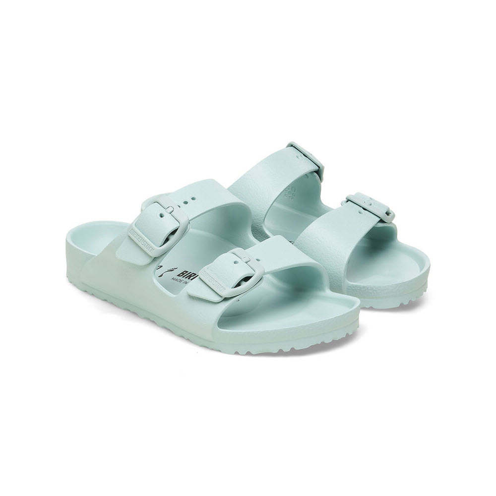 A pair of light green Birkenstock Arizona EVA Surf Green - Kids sandals with adjustable buckle straps, displayed on a white background.
