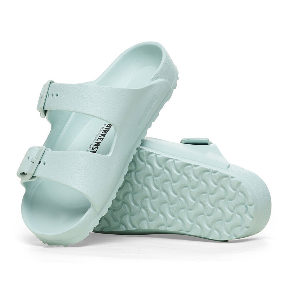 A pair of Birkenstock Arizona Eva Surf Green kids sandals with adjustable buckles and textured soles, isolated on a white background.