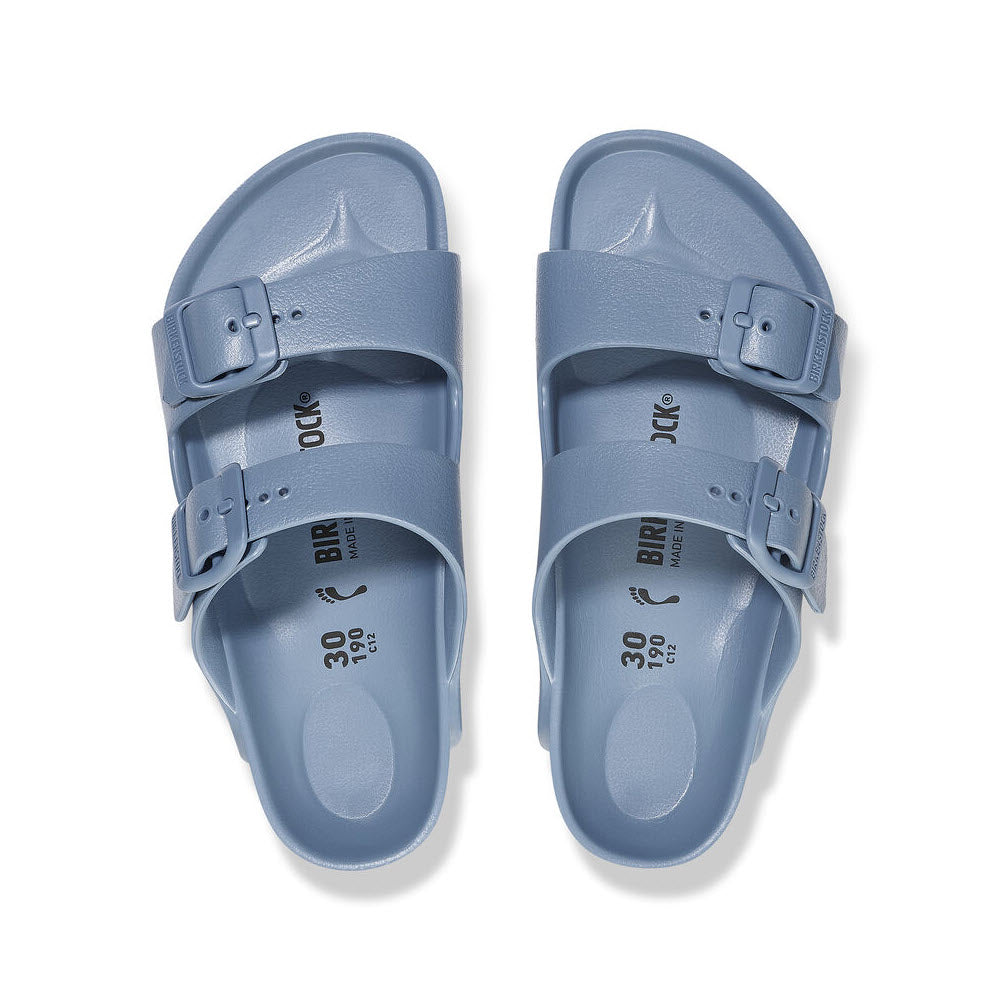 A pair of pale blue Birkenstock Arizona EVA Elemental Blue - Kids sandals with adjustable straps, viewed from above on a white background.