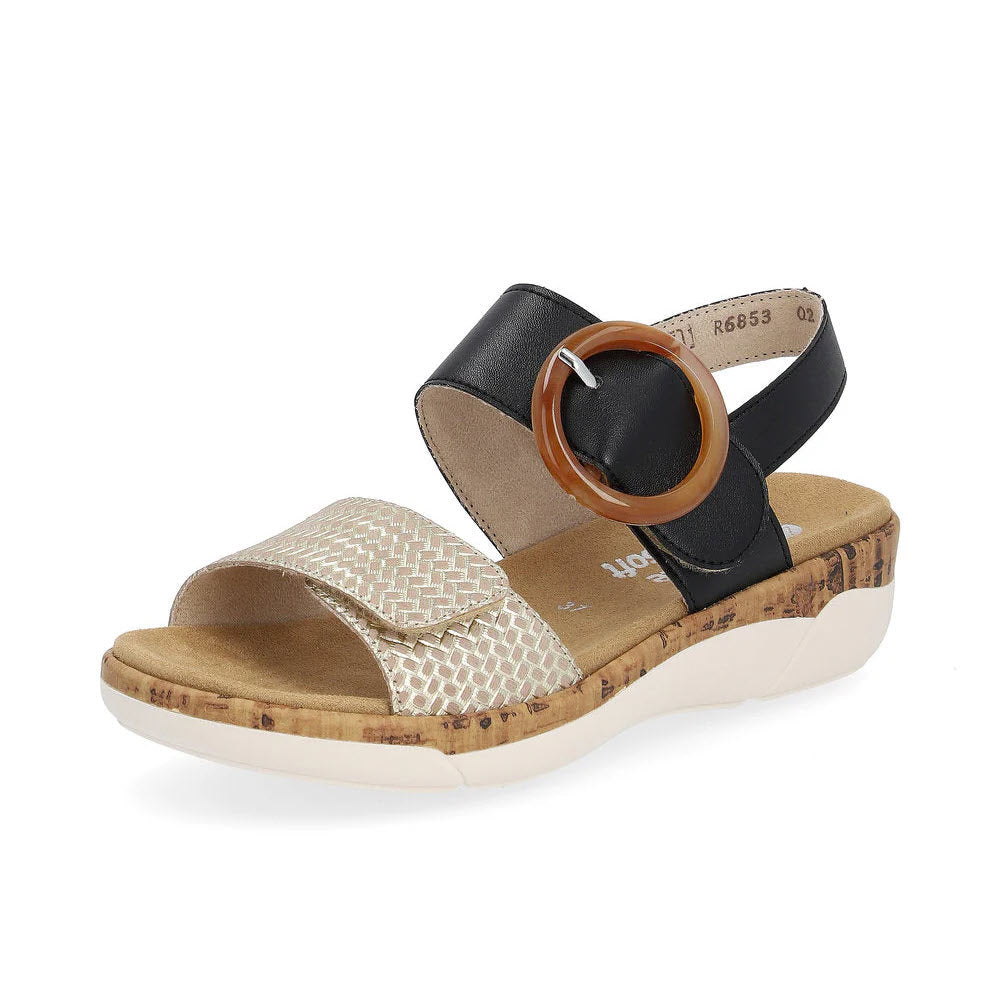 A women&#39;s sandal with a cork sole, featuring a mixed-material design with gold, black, and brown tones and a large decorative ring. Additionally, it includes a hook and loop fastener for Remonte Big Buckle Comfort Sandal in Black/Gold - Womens.