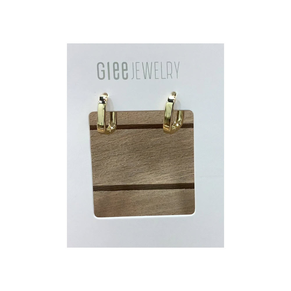 A wooden jewelry display stand with a metal clip at each top corner and the logo "Glee Jewelry" at the top, featuring Glee Petite Square Hoop Earrings Gold.