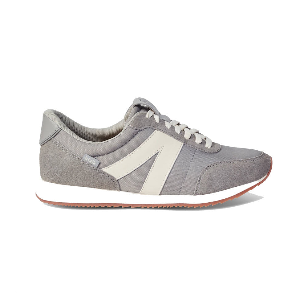 A single grey Kizik Milan Granite sneaker with white and cream accents, featuring a Kizik Milan spring-back heel and a thin orange sole, displayed against a plain background.