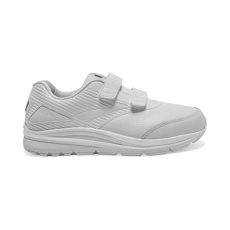 White athletic Brooks Addiction Walker V Strap 2 walking shoe with two velcro straps and a BioMoGo DNA midsole, isolated on a white background.