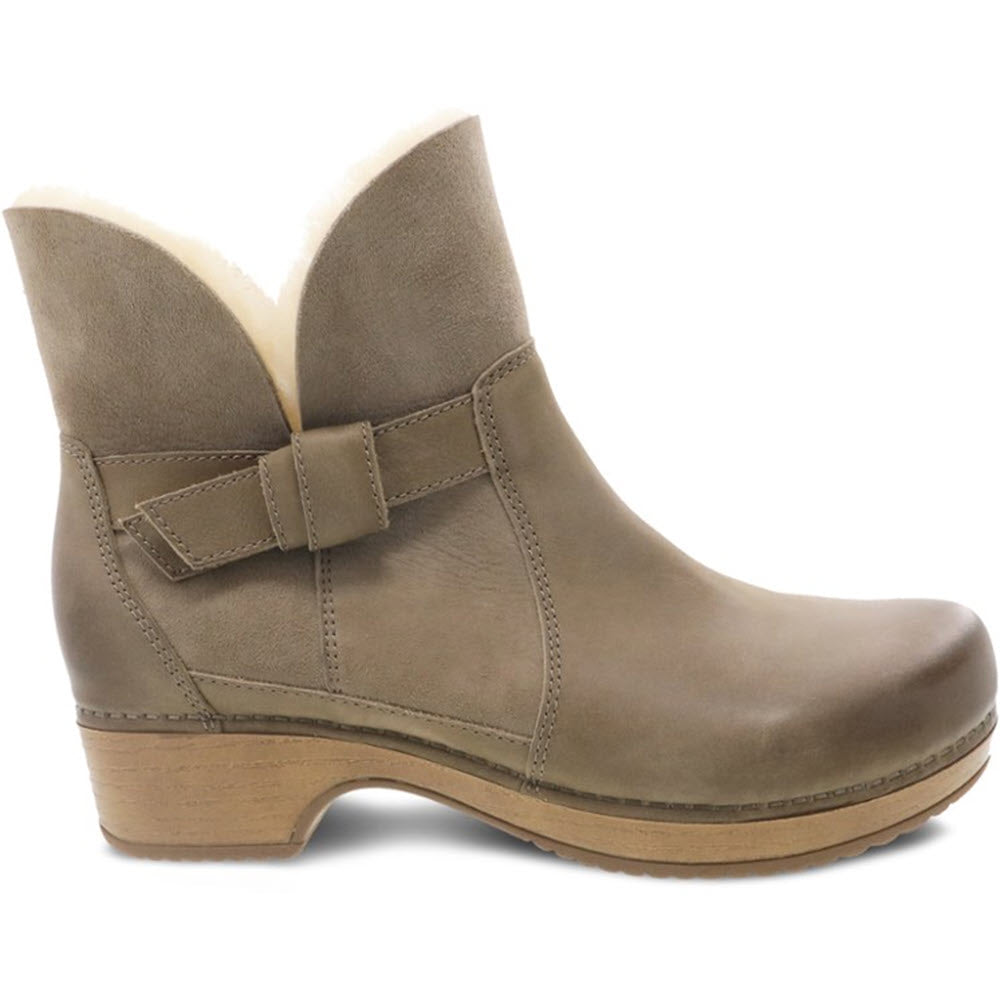 A Dansko ankle boot with a shearling lining, a buckle strap, and 3M Scotchgard protector.