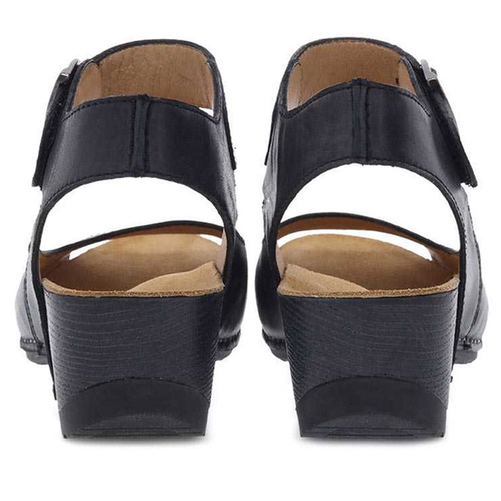 A pair of black Dansko Tiana sandals displayed from a rear view.