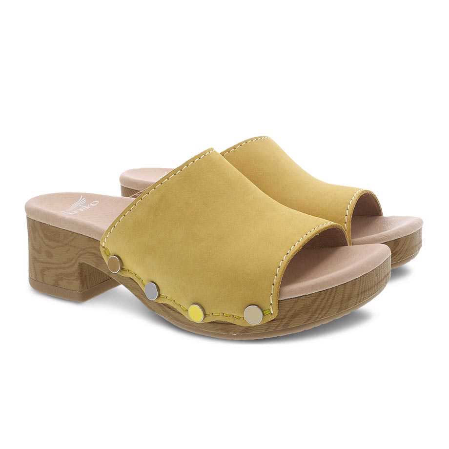 Pair of yellow Dansko Giana Yellow Milled Nubuck slide women&#39;s clog sandals with wooden soles on a white background.