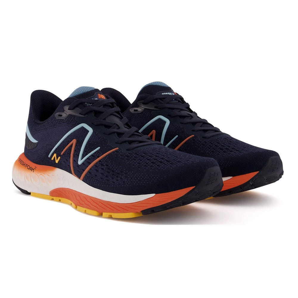A pair of New Balance 880v12 Eclipse/Vibrant Apricot running shoes with navy uppers and orange soles, featuring the brand&#39;s iconic &quot;n&quot; logo in white on the side.