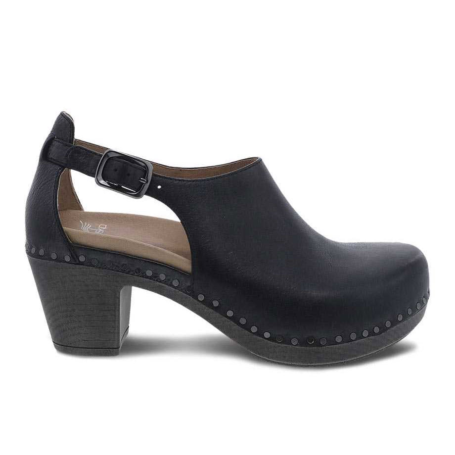 Sentence with replaced product:

Dansko Sassy Black clog with Nubuck uppers, heel, and buckle strap, featuring studded detailing around the sole.