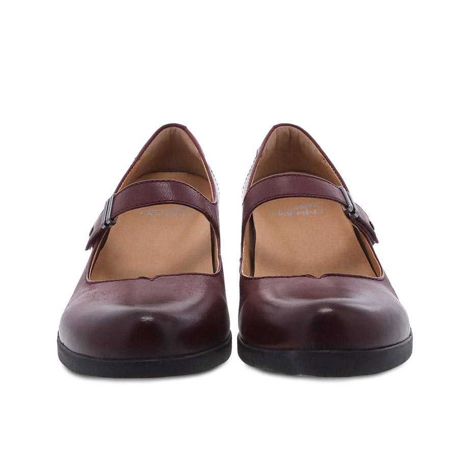 A pair of Dansko Callista wine burnished women&#39;s loafers with leather uppers and buckles, displayed against a white background.