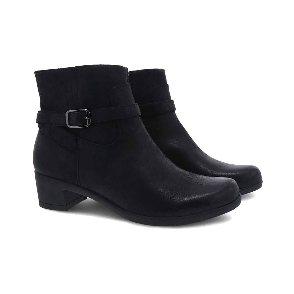 A pair of Dansko black suede heeled boots with a small heel and a decorative buckle strap.