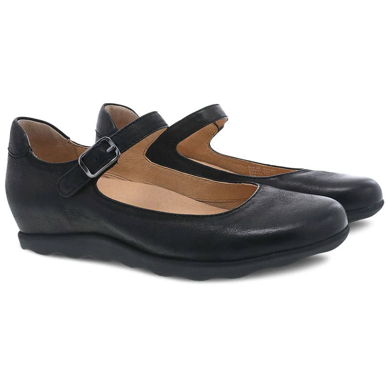 A pair of black Dansko Marcella Mary Jane style women&#39;s shoes with a single buckle strap, featuring Dansko Natural Arch technology.