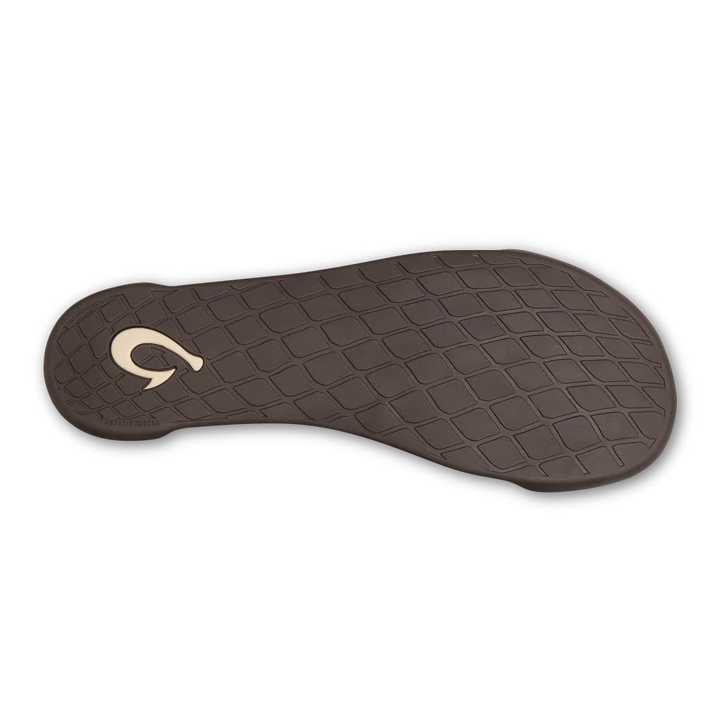 A sole of a Olukai Kipuka Hulu Toffee/Toffee slipper with a brown tread pattern and a logo in the center, constructed from durable nubuck leather.