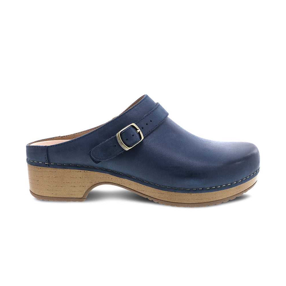Dansko navy blue leather clog with an adjustable ankle strap, wooden sole, and visible stitching, isolated on a white background.