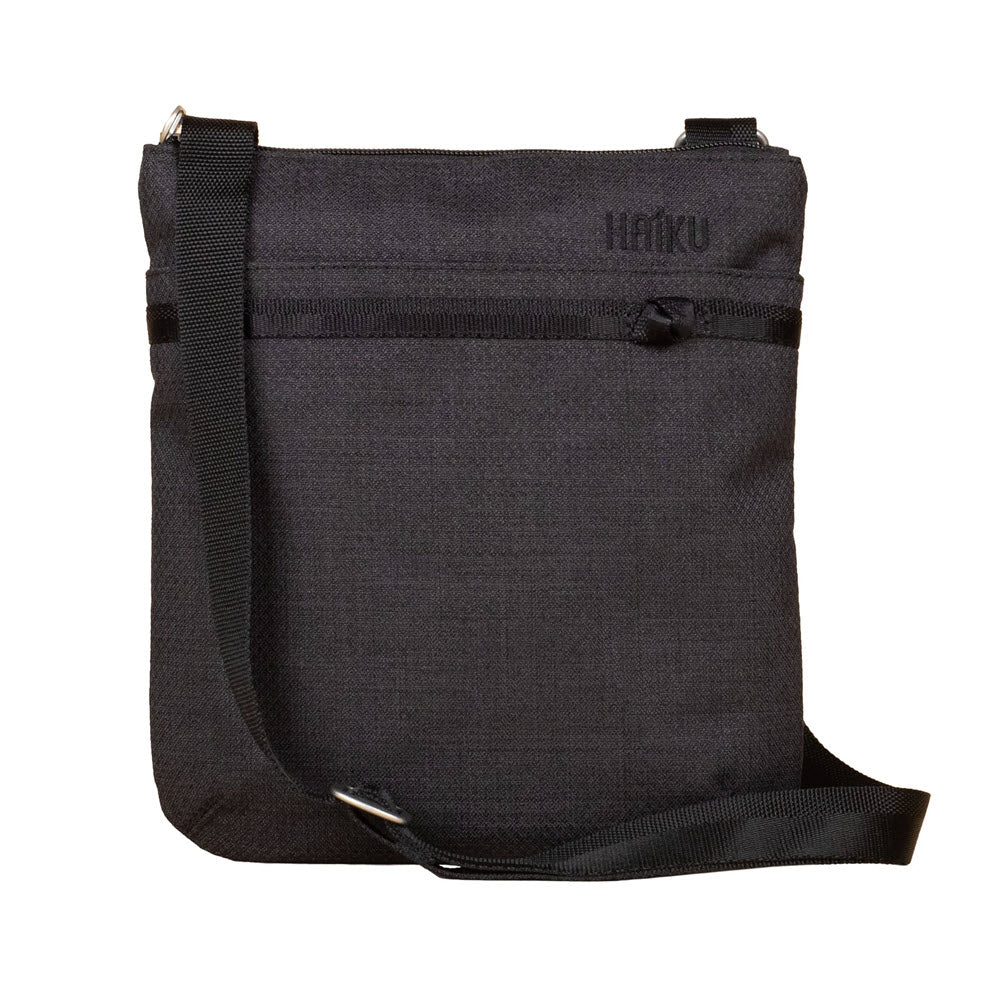 Sentence with replaced product and brand names: HAIKU REVEL CROSSBODY BAG BLACK IN BLOOM with adjustable strap and toggle-locking zipper, labeled "Haiku" on the front flap.