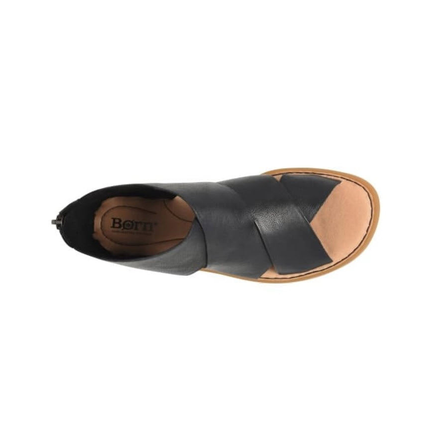 Top view of a black ultra-soft leather slip-on sandal with a tan insole and branded with &quot;BORN IMANI BLACK - WOMENS&quot; on the footbed, isolated on a white background.