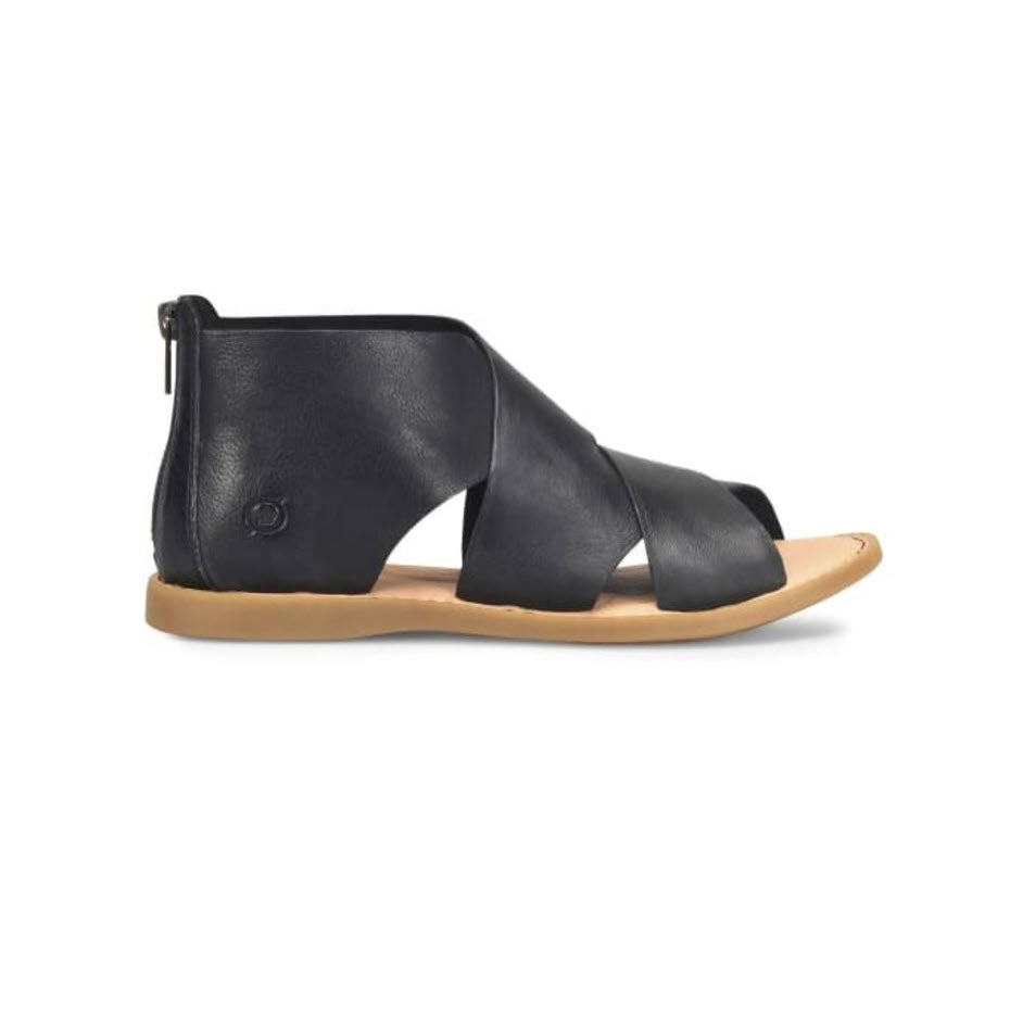 Born black ultra-soft leather flat sandal with a zipper on the heel and crisscross straps, isolated on a white background.