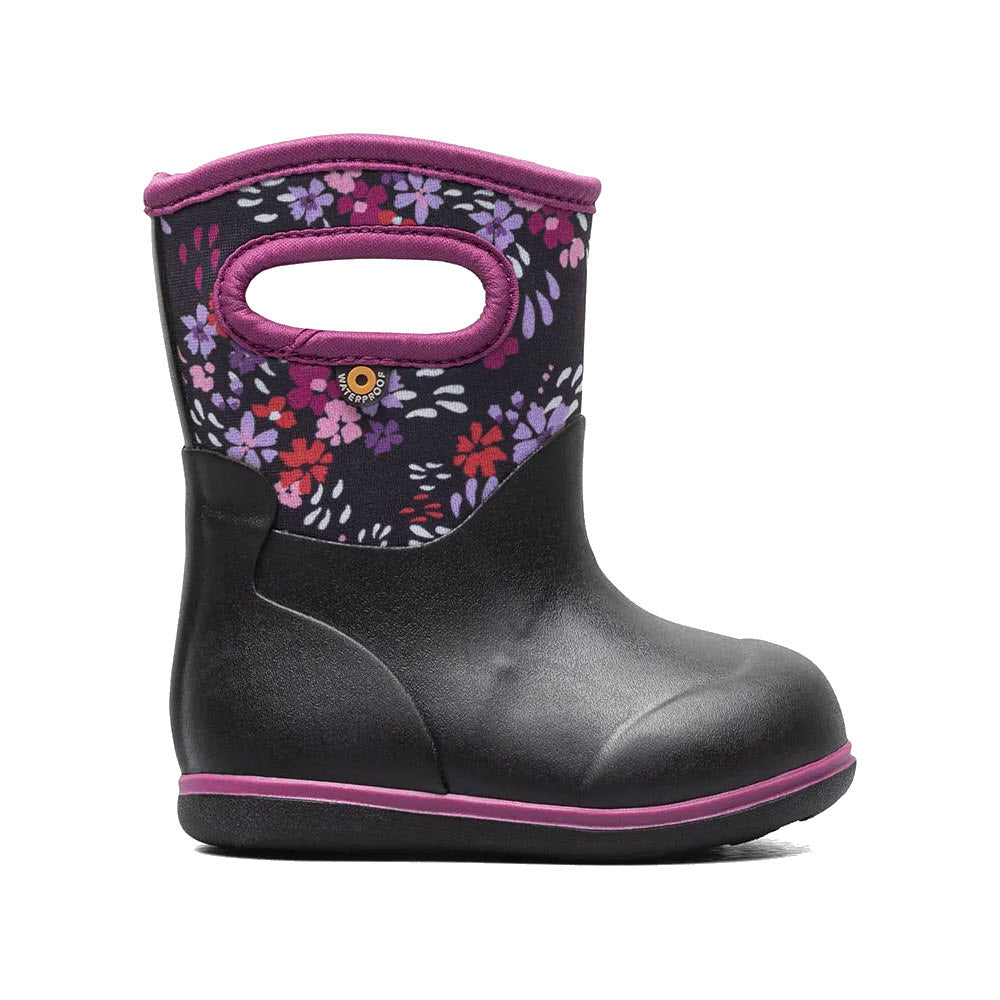 A toddler-ready, waterproof child's winter boot from Bogs featuring a black base with a floral pattern on a dark purple background, complemented by a pink sole and a pull-on handle.