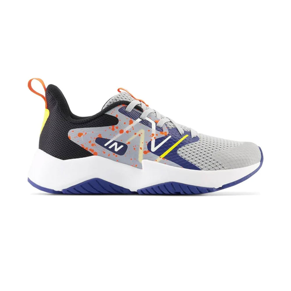 A modern New Balance kids&#39; running shoe featuring a gray and white upper, blue soles, orange speckles, and a visible &quot;n&quot; logo on the side.