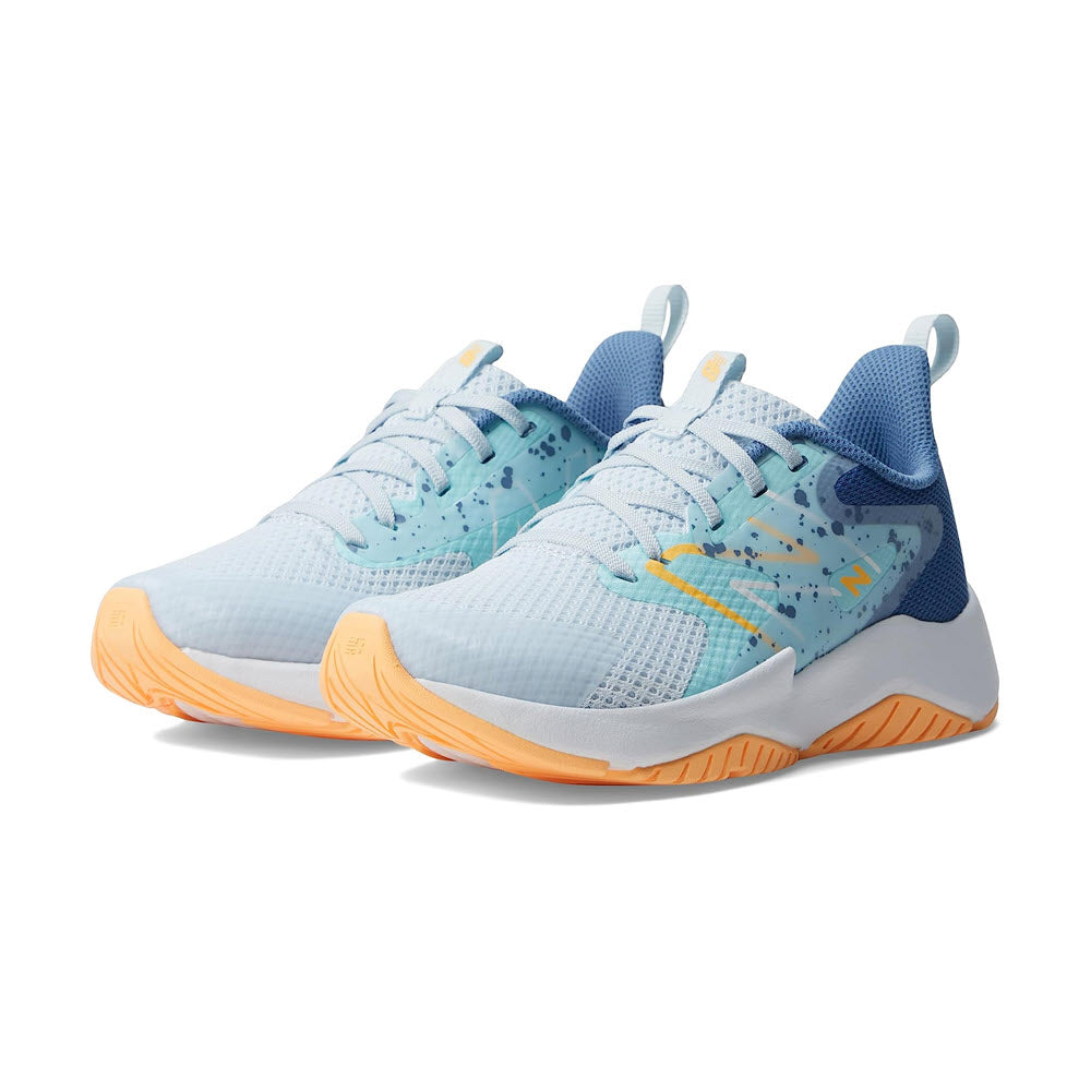 A pair of light blue and navy New Balance Rave Run v2 kids’ running shoes with speckled details and bright yellow soles.