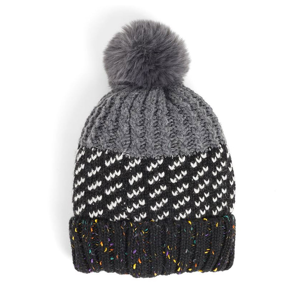 A COCO & CARMEN Lumi Hat Black with a black and white pattern and a dark, fluffy pom-pom on top, isolated on a white background. This cozy hat is perfect for chilly weather.