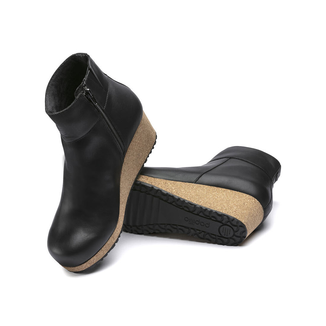A pair of Birkenstock Papillio Ebba Black Leather ankle boots with zippers, featuring cork midsoles and black rubber outsoles, displayed on a white background.