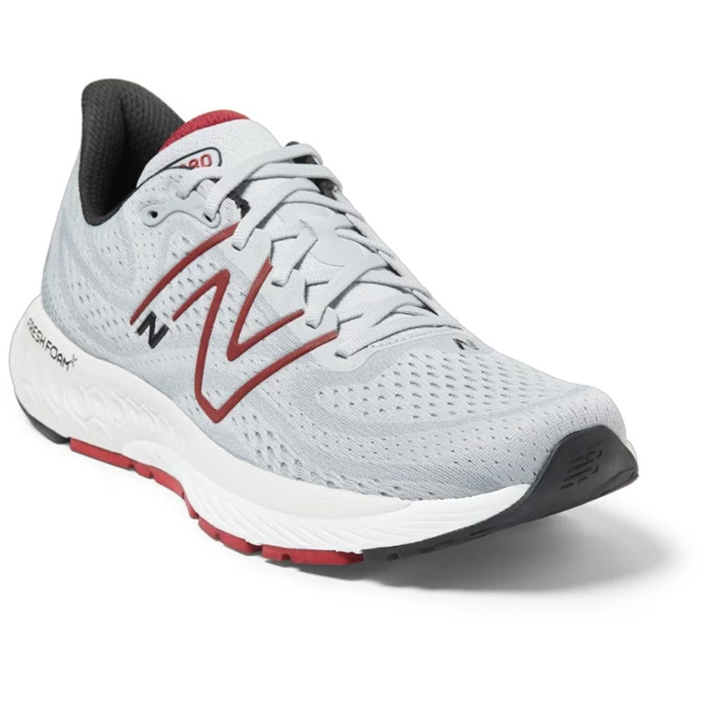 A new New Balance 880v13 running shoe in white and gray with red accents, featuring a prominent &#39;n&#39; logo on the side.