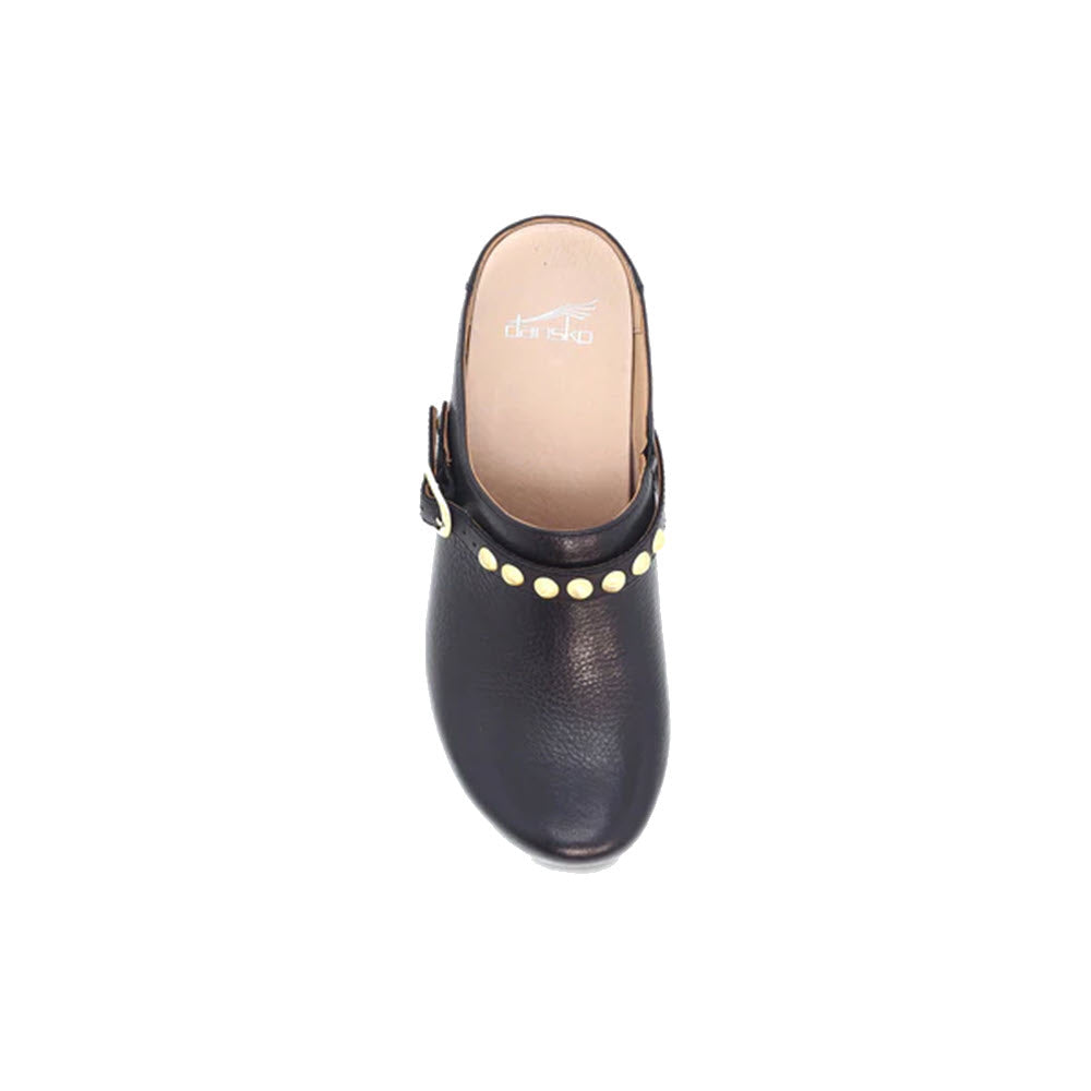 Top view of a single Dansko Britton Black leather clog with a buckle and silver hardware details around the edge, isolated on a white background.