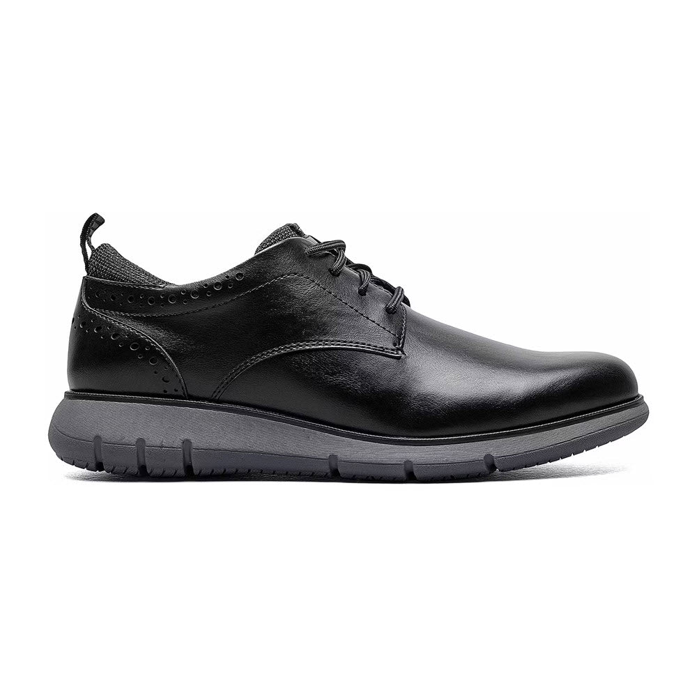 A black leather Nunn Bush Stance Plain Toe Oxford men's dress shoe with lace-up closure and a thick rubber sole, isolated on a white background.