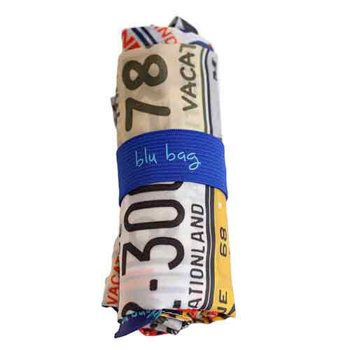 A rolled-up BLU BAG MAINE LICENSE PLATE shopping bag with vintage Maine license plates patterned graphics, secured by a blue elastic band labeled &quot;blu bag.
