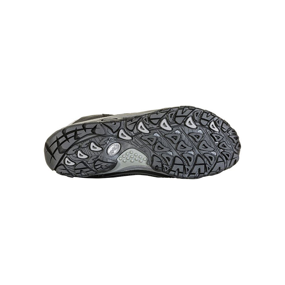 A close-up of a Oboz Sapphire 8&quot; Insulated B Dry Black - Women&#39;s winter hiker shoe&#39;s sole featuring a complex tread pattern and a circular logo, set against a plain white background.