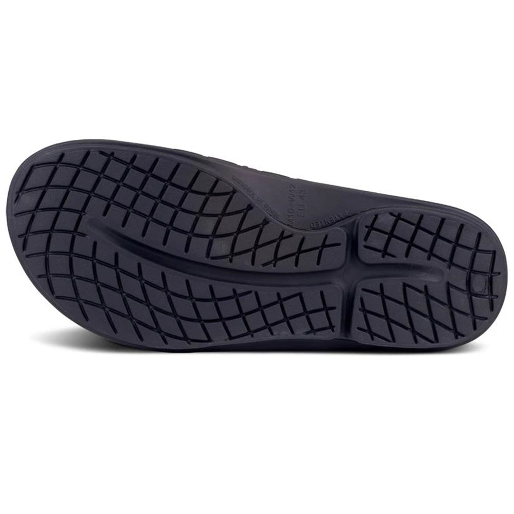 Black rubber sole of an Oofos athletic shoe with a grid tread pattern, viewed from below.