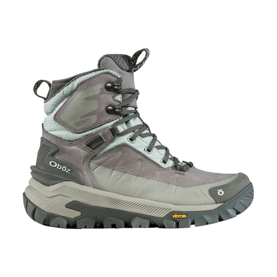 A single Oboz Bangtail Mid Insulated Bdry Winter Quartz hiking boot for women featuring a high-top design, gray and pale blue colors, camouflage detailing, and Vibram Arctic Grip outsoles.