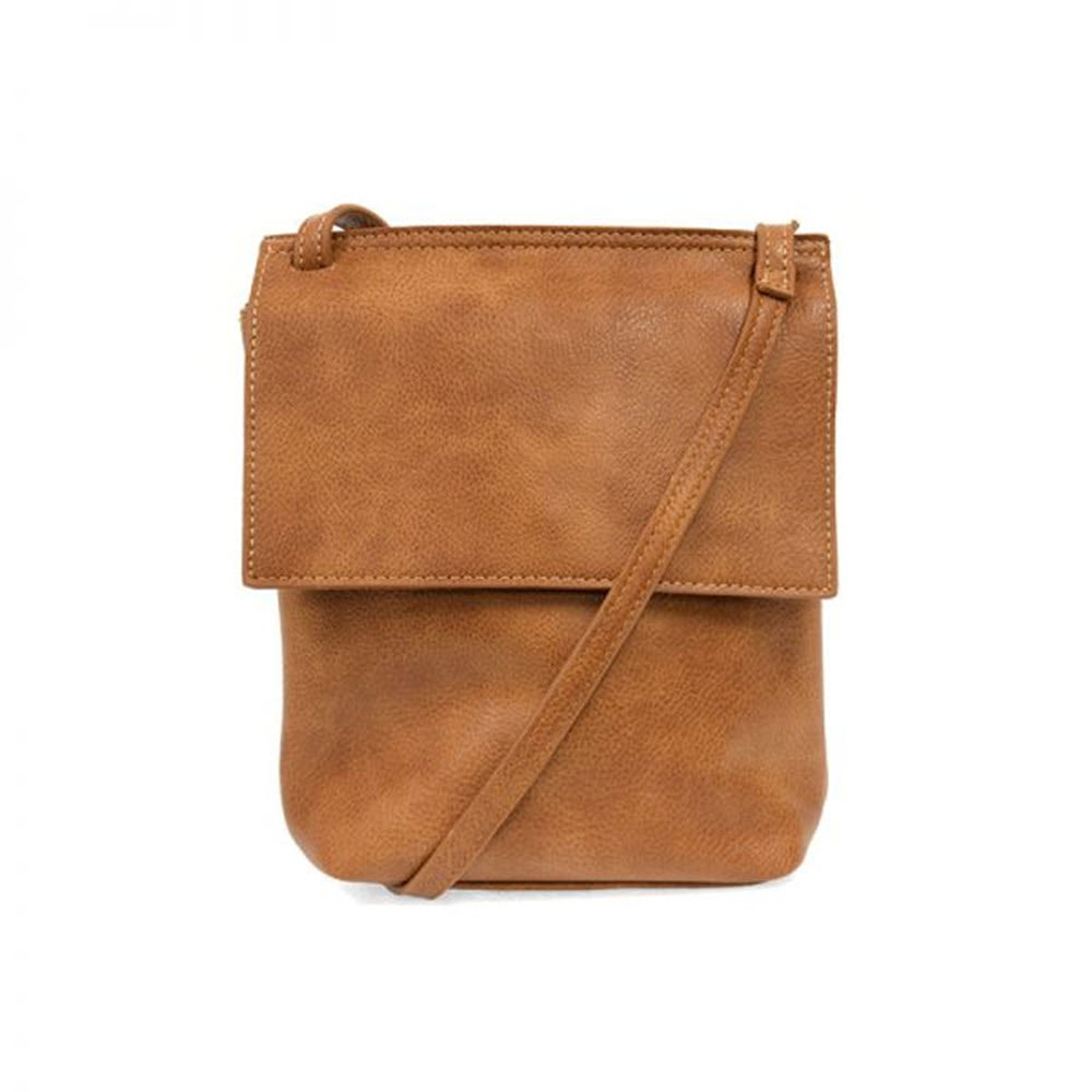 A brown vegan leather Joy Susan crossbody bag with a flap closure and a single strap, isolated on a white background.