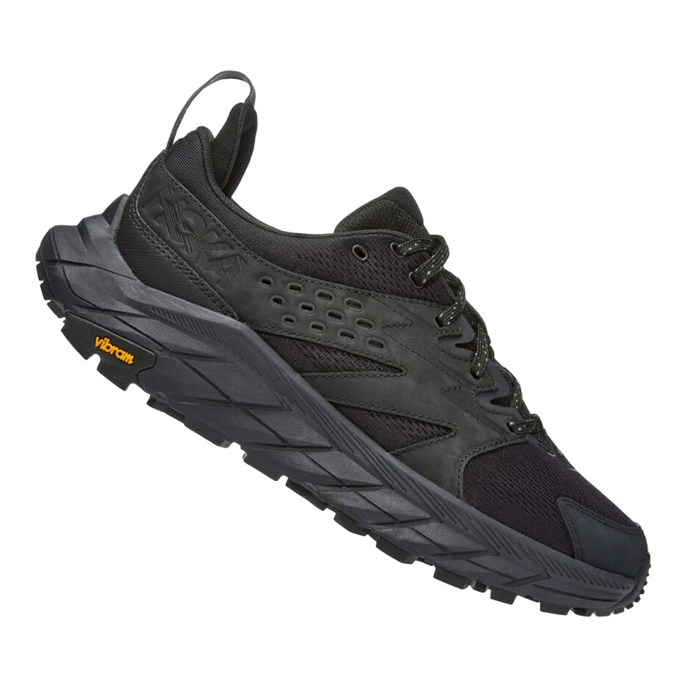 A single HOKA ANACAPA BREEZE LOW BLACK/BLACK - MEN trail running shoe with a rugged sole and Vibram® Megagrip outsole label on the side, isolated on a white background.