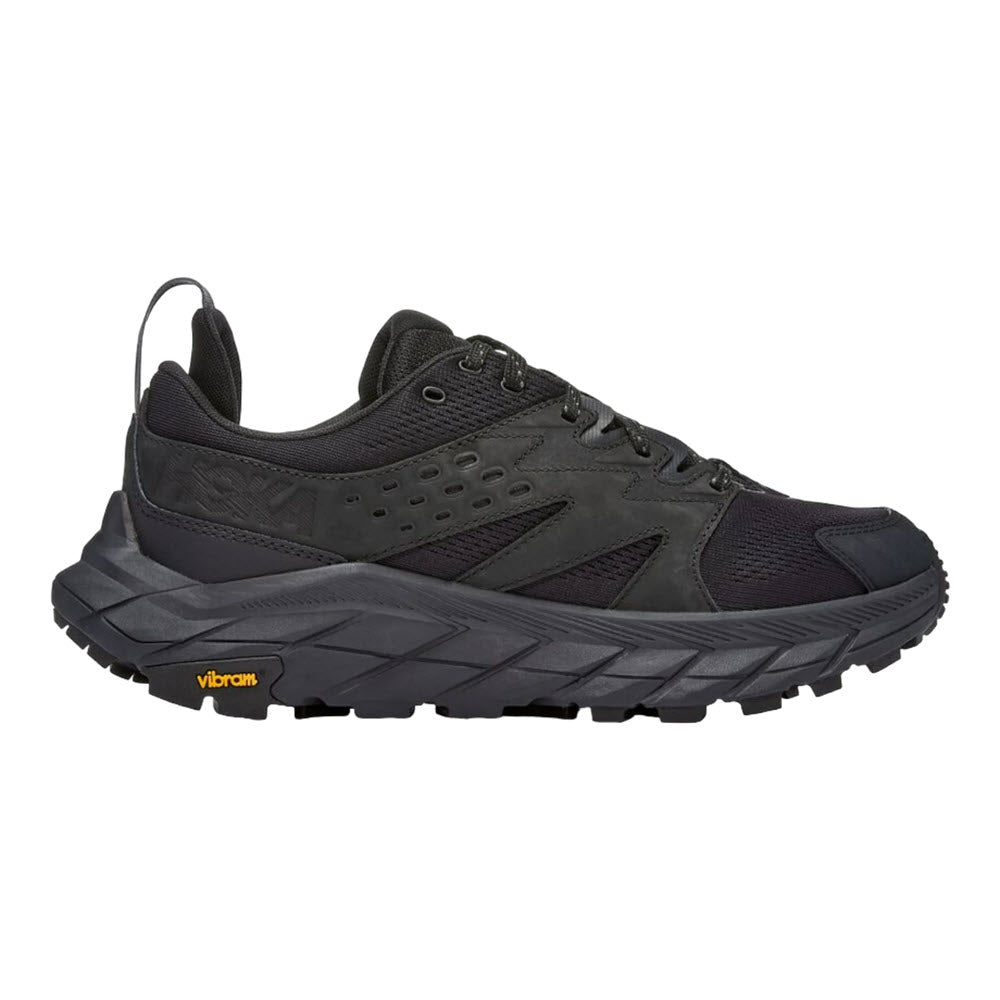 Black Hoka ANACAPA BREEZE LOW hiking shoe with a Vibram® Megagrip outsole, featuring a lace-up design and perforations for breathability, isolated on a white background.