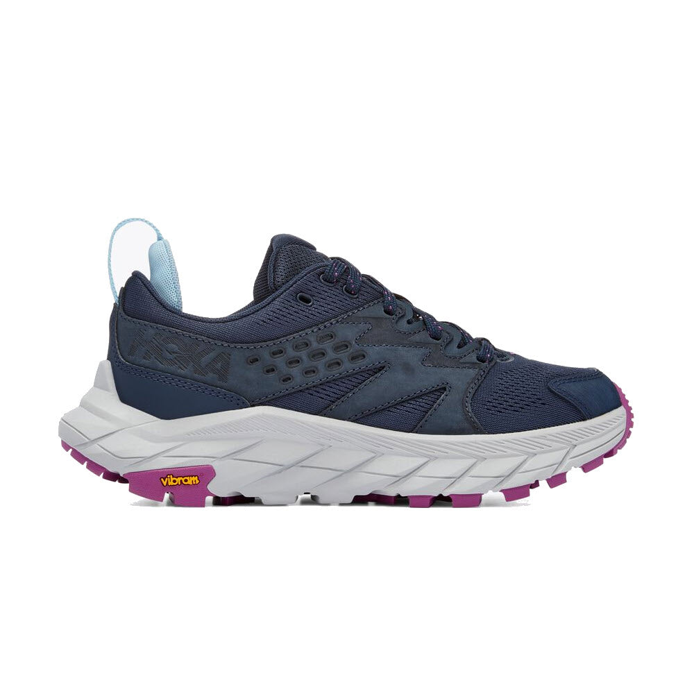 A navy blue Hoka Anacapa Breeze Low Outer Space/Harbor Mist trail running shoe with a white Vibram Megagrip outsole and purple accents on the tread, showcasing a side view.