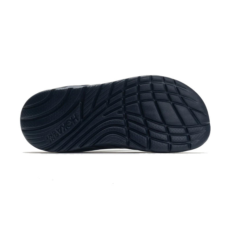 Bottom view of a black Hoka athletic shoe showcasing its oversized midsole, textured sole pattern, and brand logo.